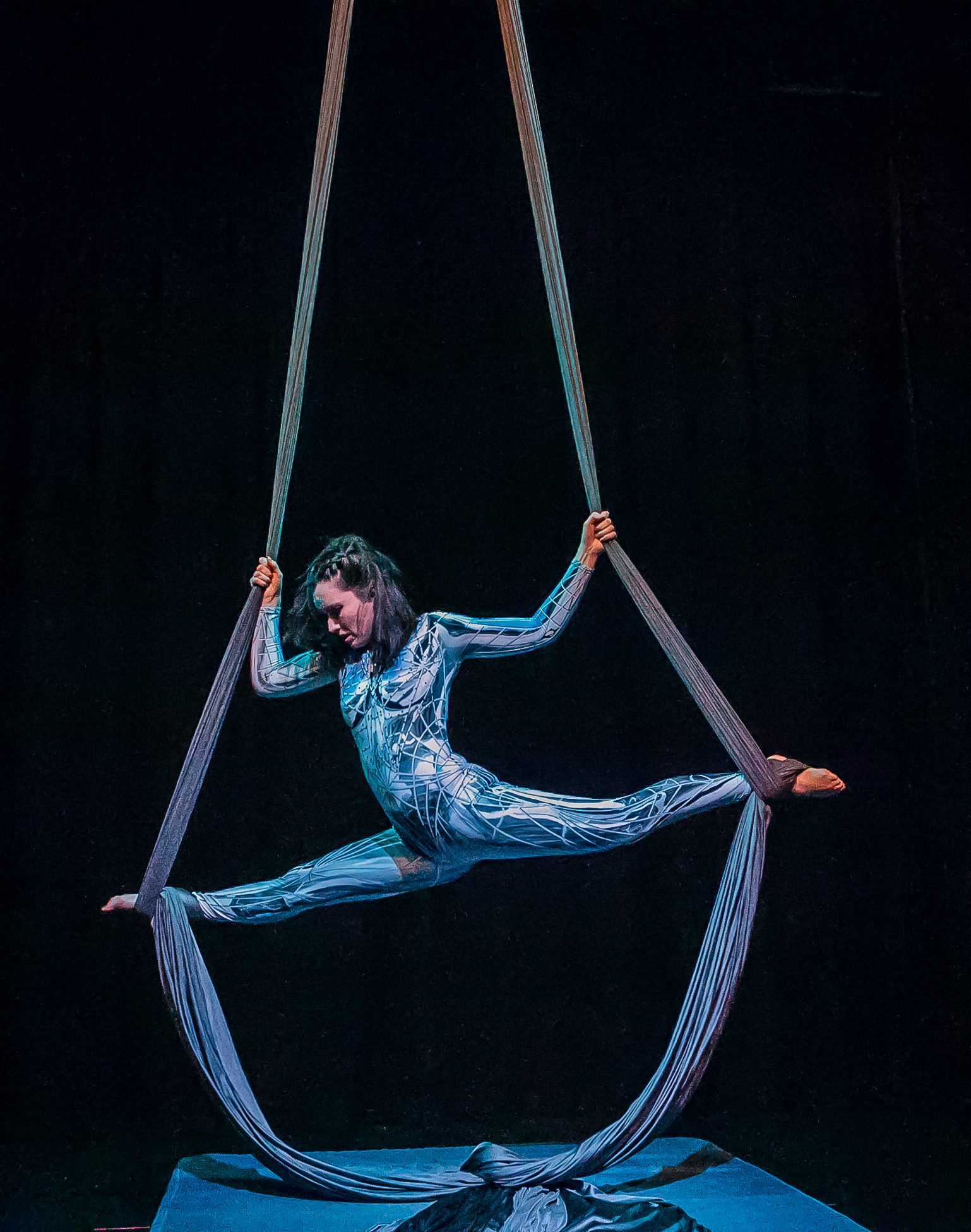 Silks performer in a split pose